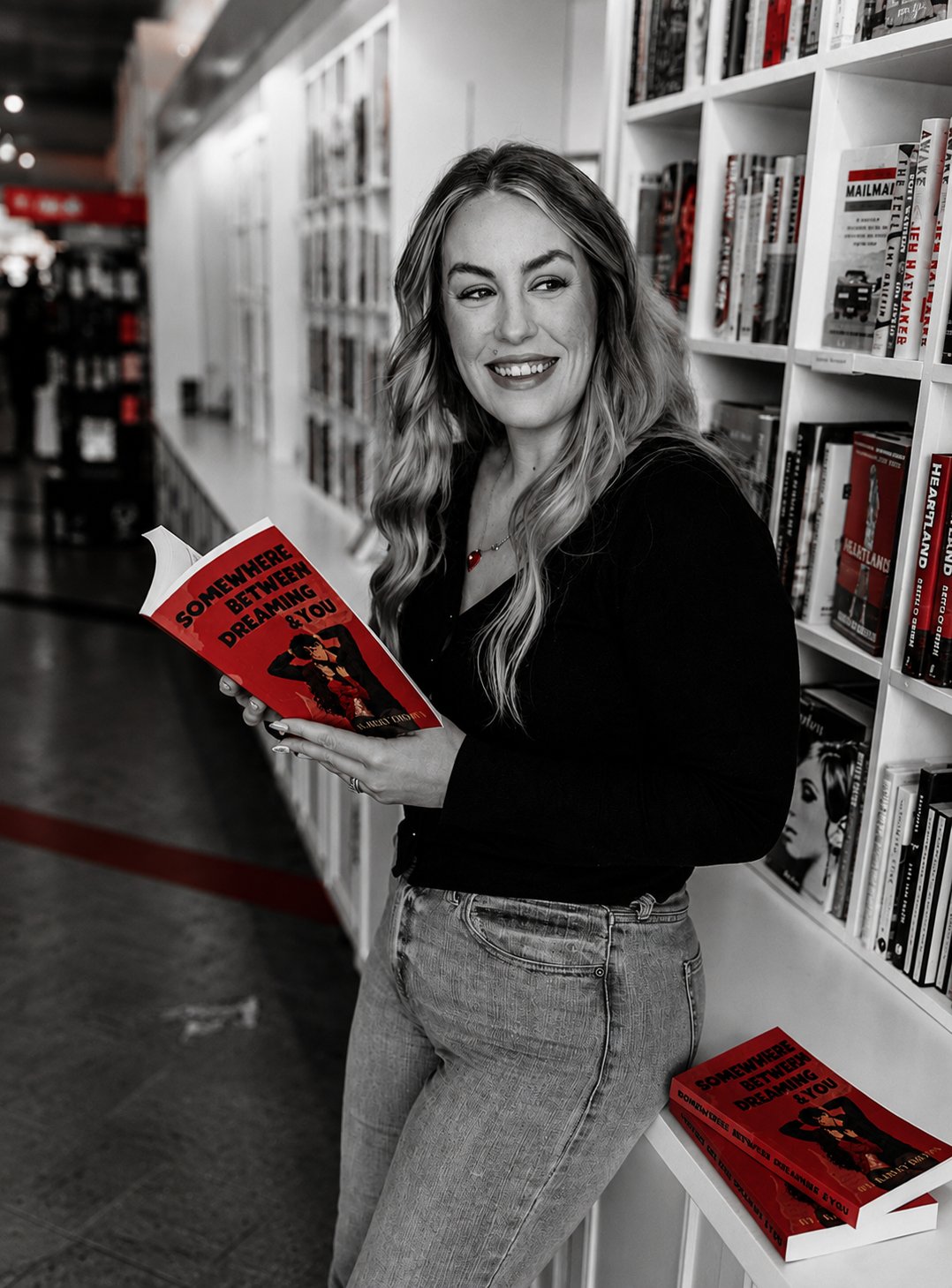Kailey Brown holding an open book in a bookstore aisle